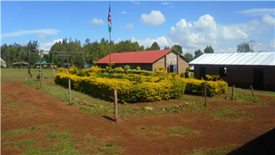 Our schoolyard including the red-roofed church, one of the metal-roofed classrooms, and the Kenyan flag in the middle