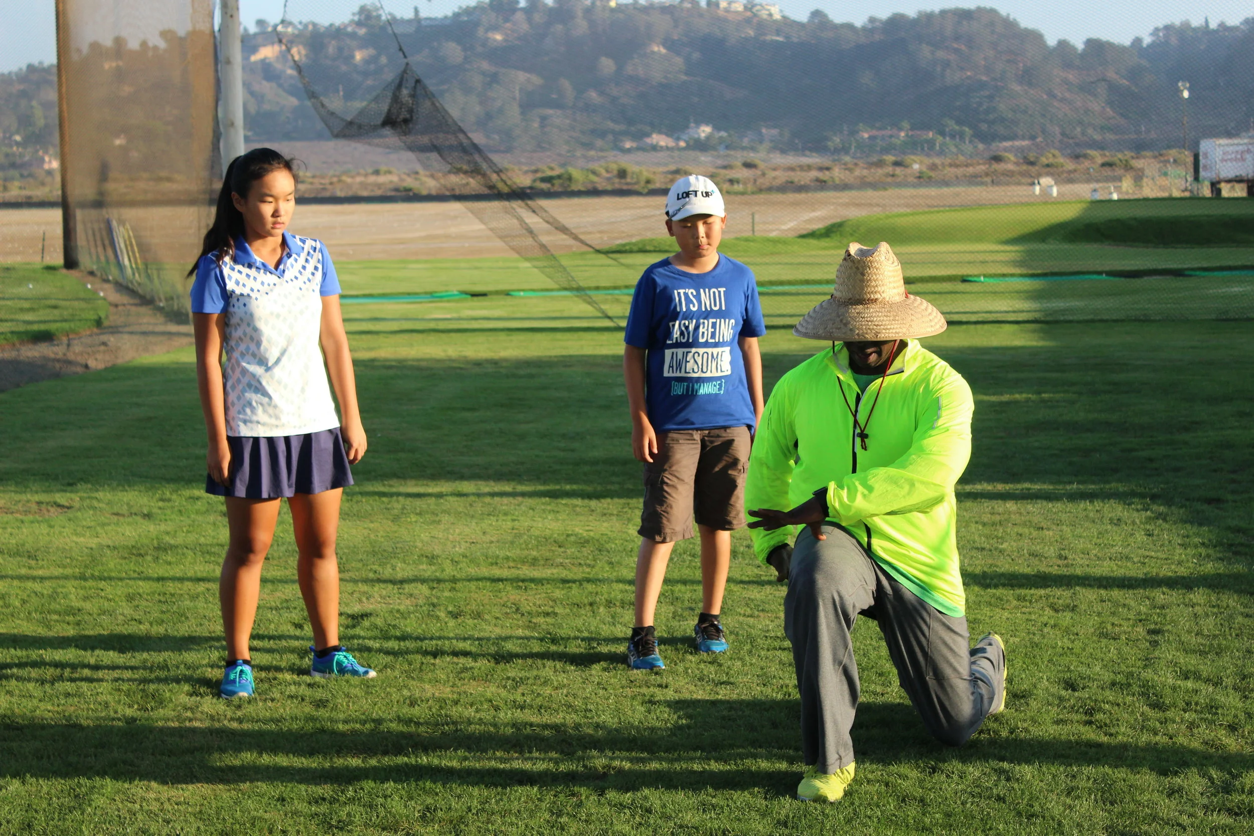 Coach Milo showing a group of young athletes proper form during a workout session.