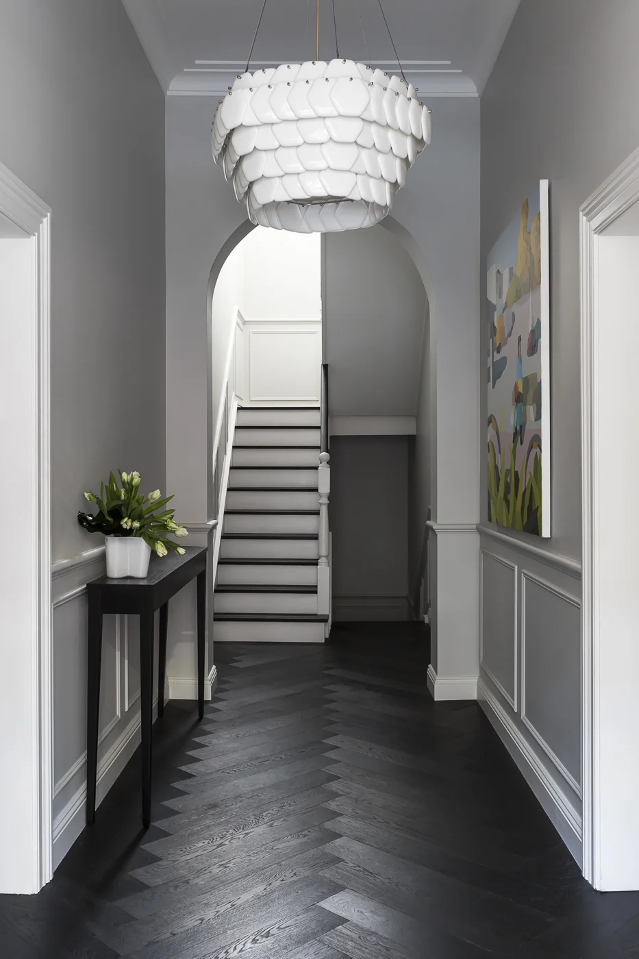 An elegant foyer proudly reveals strong features such as the new herringbone timber flooring, wall paneling and sculptural pendant light.