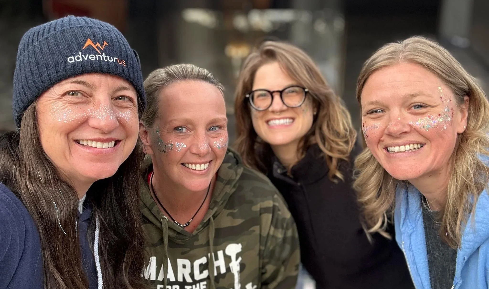 Four smiling Camp AdventurUs attendees wearing AdventurUs gear at a women's outdoor retreat in Oregon.