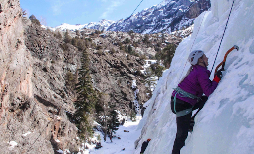 Kaitlin Heatherly is climbing a snowy mountain using climbing gear.