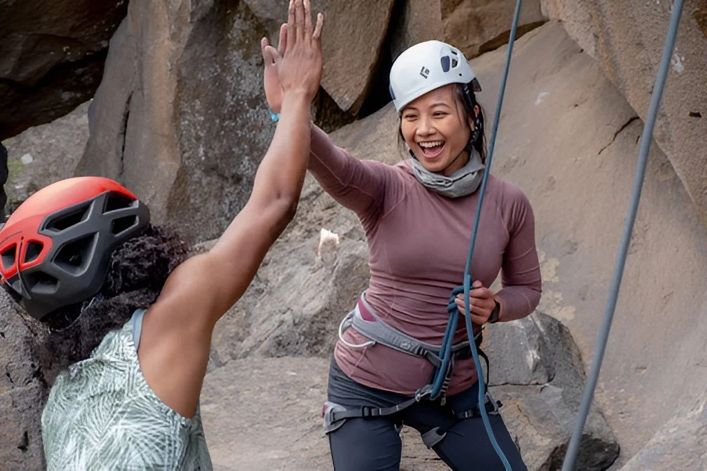 Women rock climbing with guide support during a beginner-friendly outdoor adventure activity organized by AdventurUs.