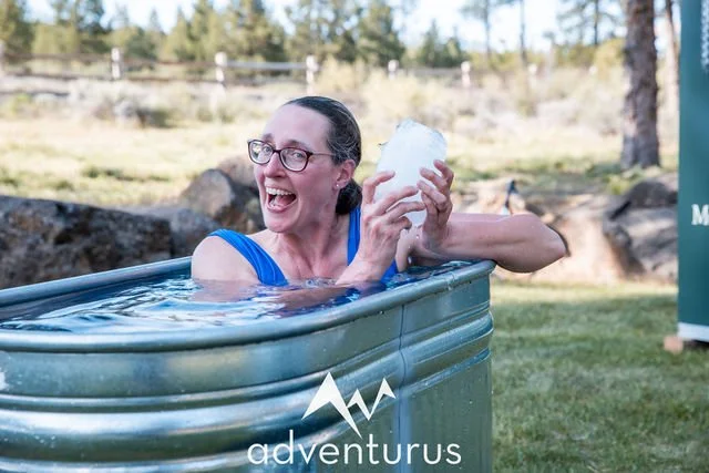 Rachel holding ice in a cold plunge tub during an outdoor wellness session.
