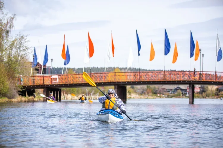 Woman kayaking on the Deschutes River in Bend as part of a guided outdoor adventure trip organized by AdventurUs.