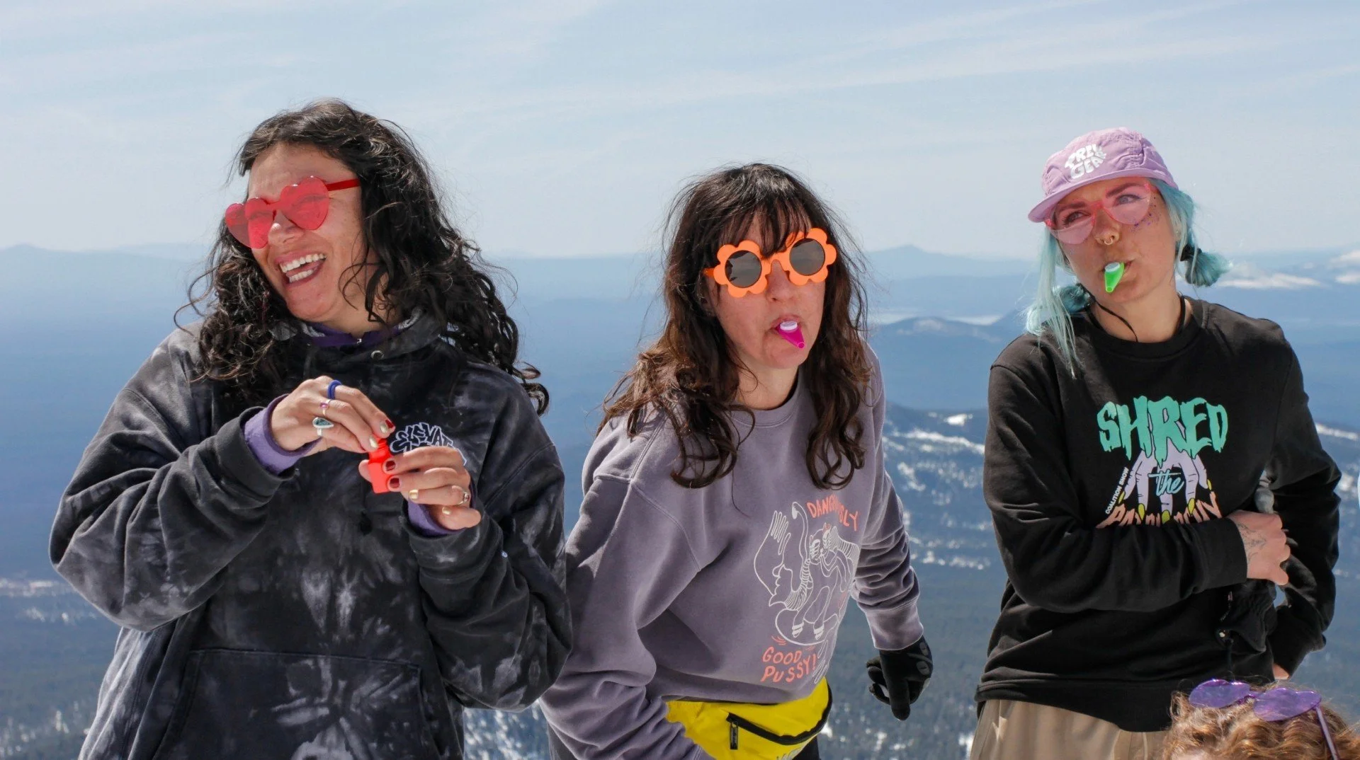 Jen Gurecki with friends on a snowy mountain summit, enjoying a playful moment outdoors during a winter adventure.