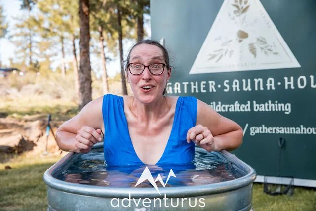 Rachel smiling in a cold plunge tub during an outdoor wellness experience.