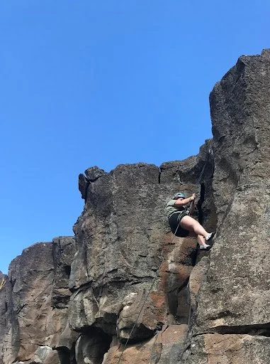 Elle is climbing the rock mountain during the adventure camp organised by AdventurUs.