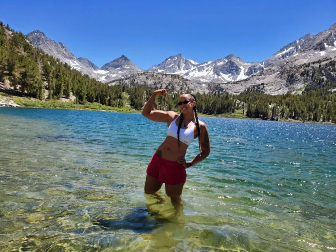 Nicole Snell posing in a lake with mountains in the backdrop.