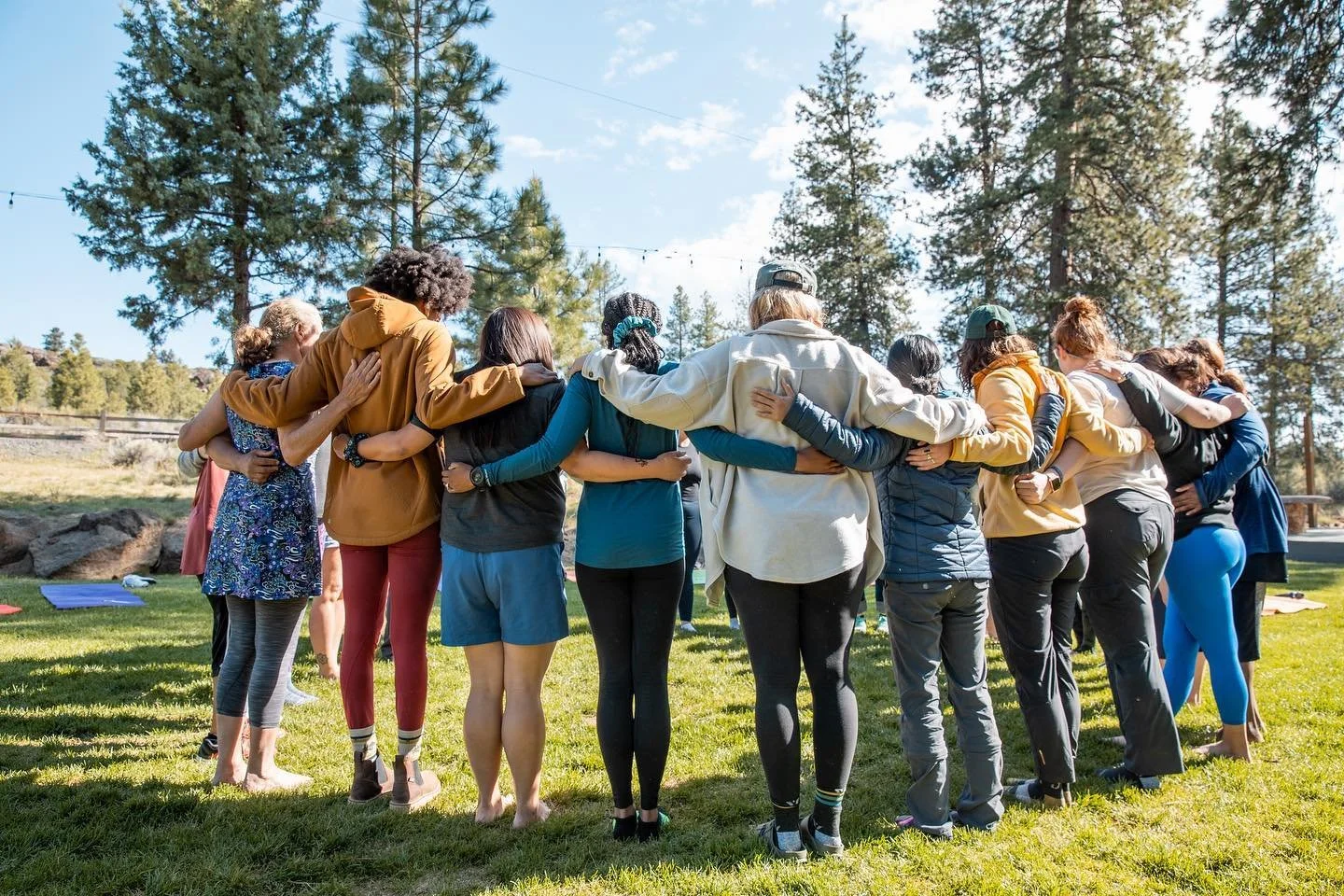 Group of women standing arm in arm outdoors at the end of a women’s adventure camp organized by AdventurUs.