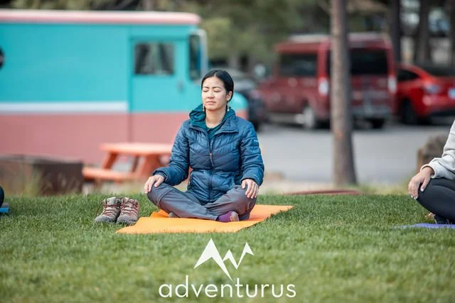 AdventurUs guest meditating on a yoga mat during a peaceful outdoor wellness session.