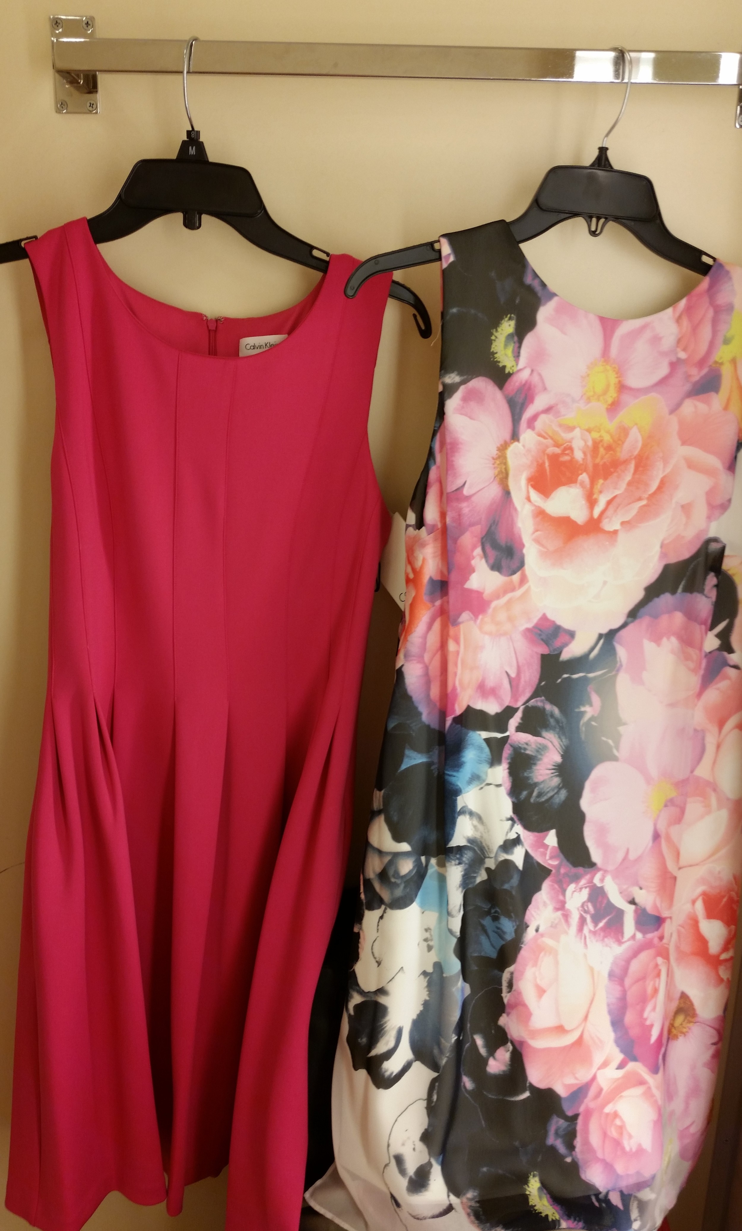 On the left is a Calvin Klein simple pleated sleeveless dress in a beautiful shade of magenta or hot pink. On the right is a sleeveless printed Vince Camuto number. There is a cream colored sheath underneath a beautiful floral printed overlay. 