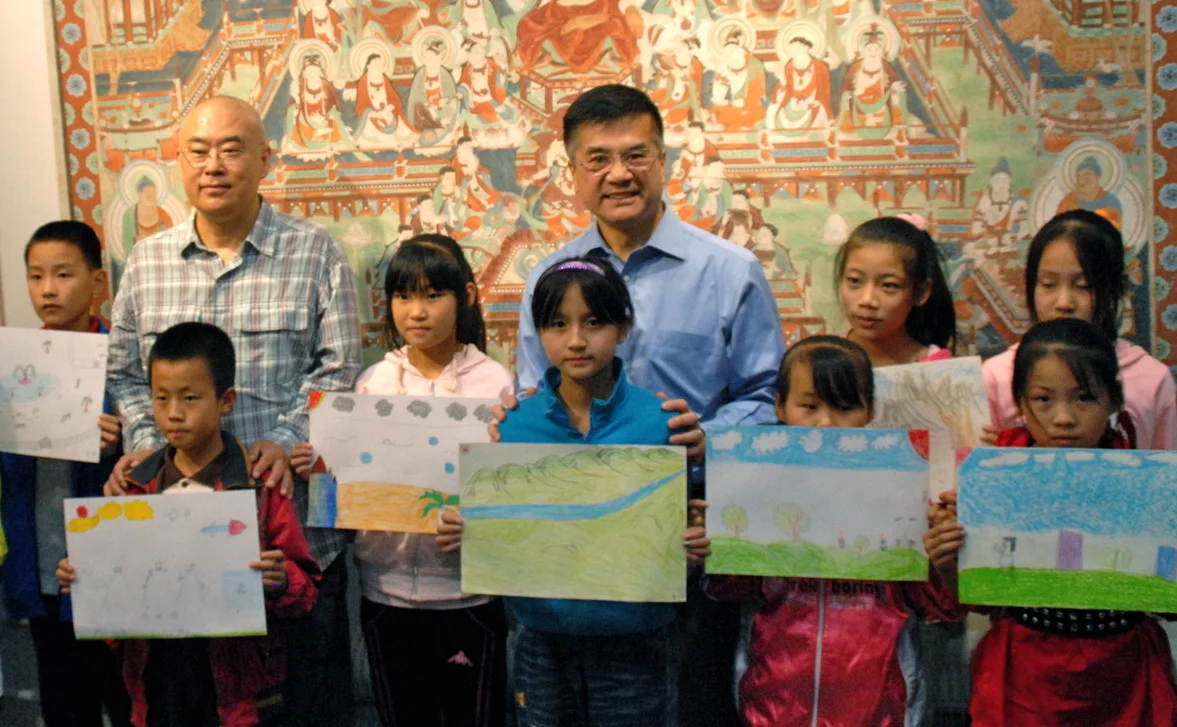 Author Zheng Yuanjie (left) and US Ambassador Gary Locke pose with migrant children and their "Peace" artwork. Some of the art was later given to the US Embassy in Beijing. (Courtesy of US Embassy, Beijing)