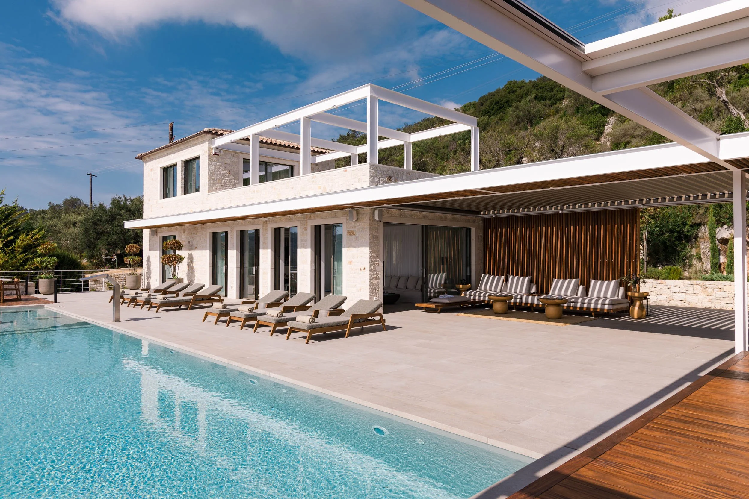 Modern house with a swimming pool and outdoor lounge chairs on a sunny day.
