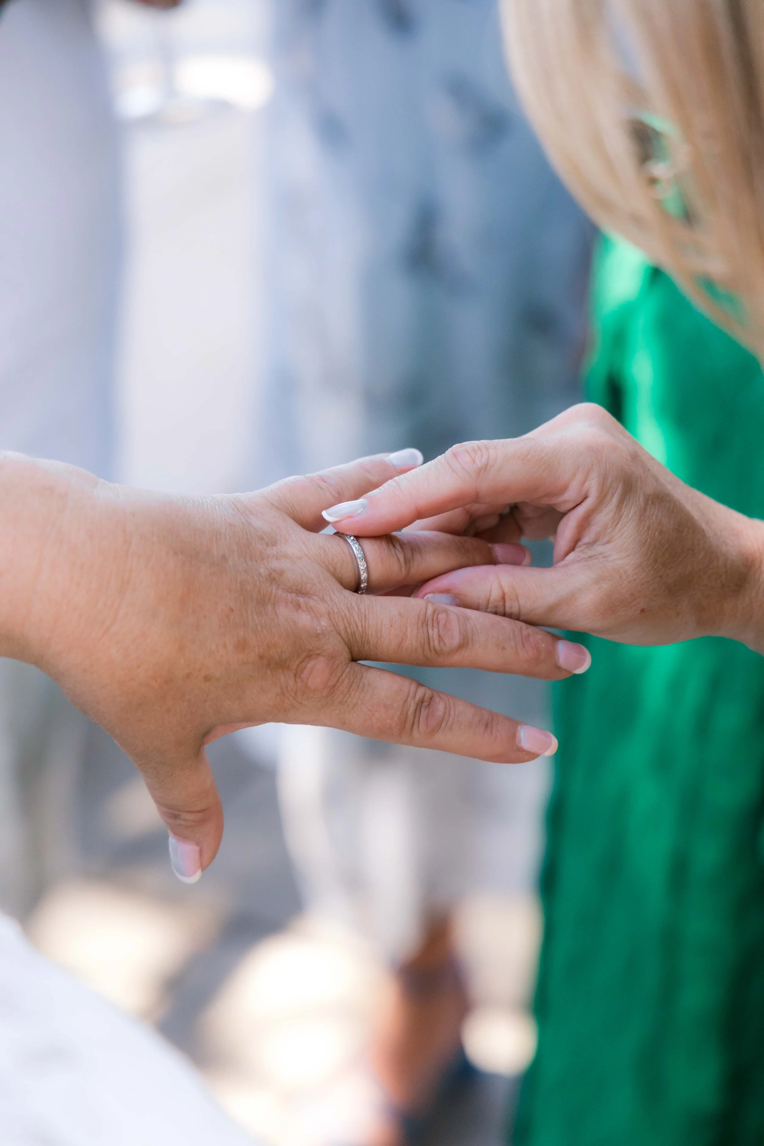 Close-up of two women's hands, one wearing a wedding ring, gently holding each other.