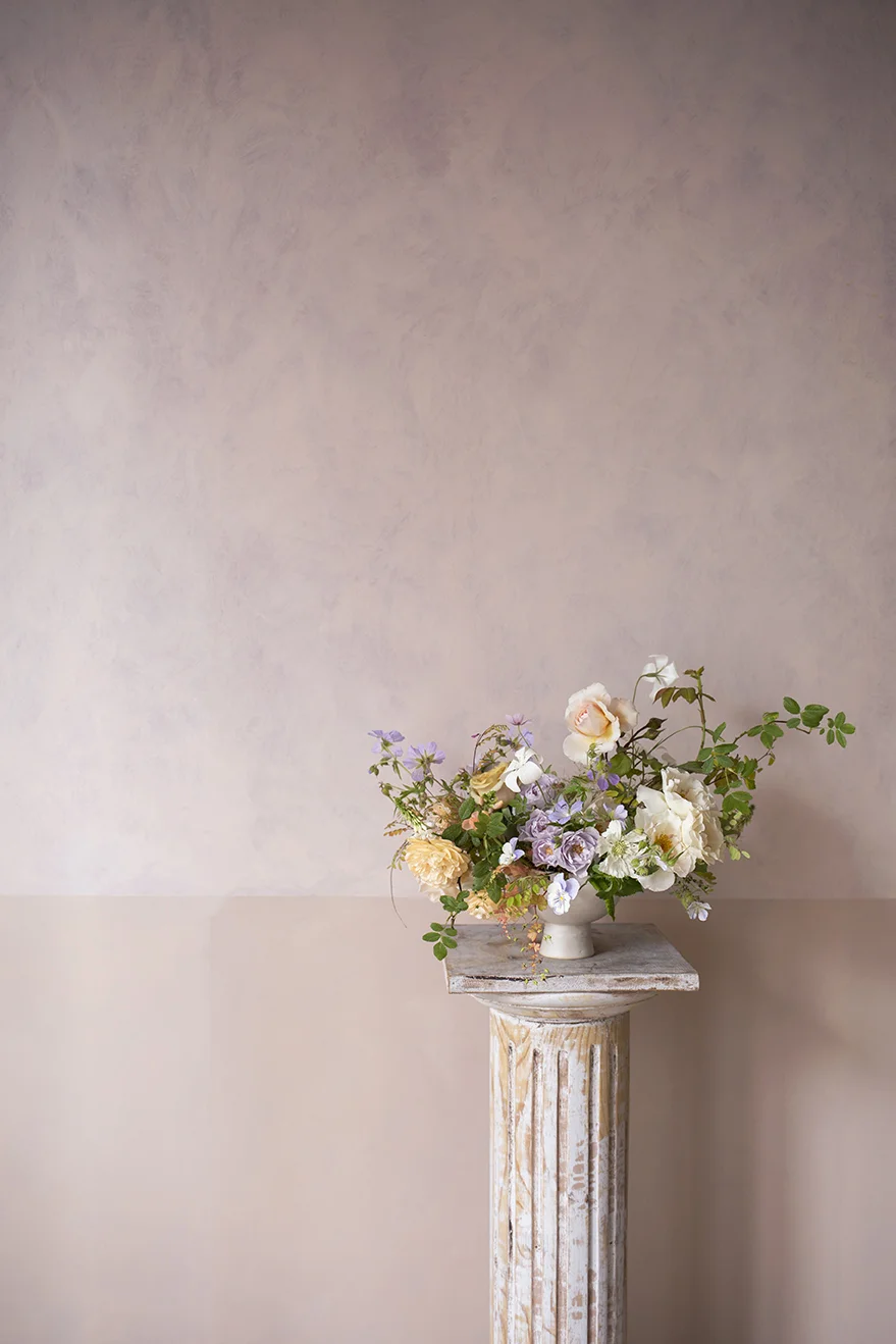 A 'demo' table centrepiece in a ceramic footed bowl. A palette of creamy yellow, lavender and white. Garden roses, geranium pansies, agrostemma, scabiosa and herb Robert.