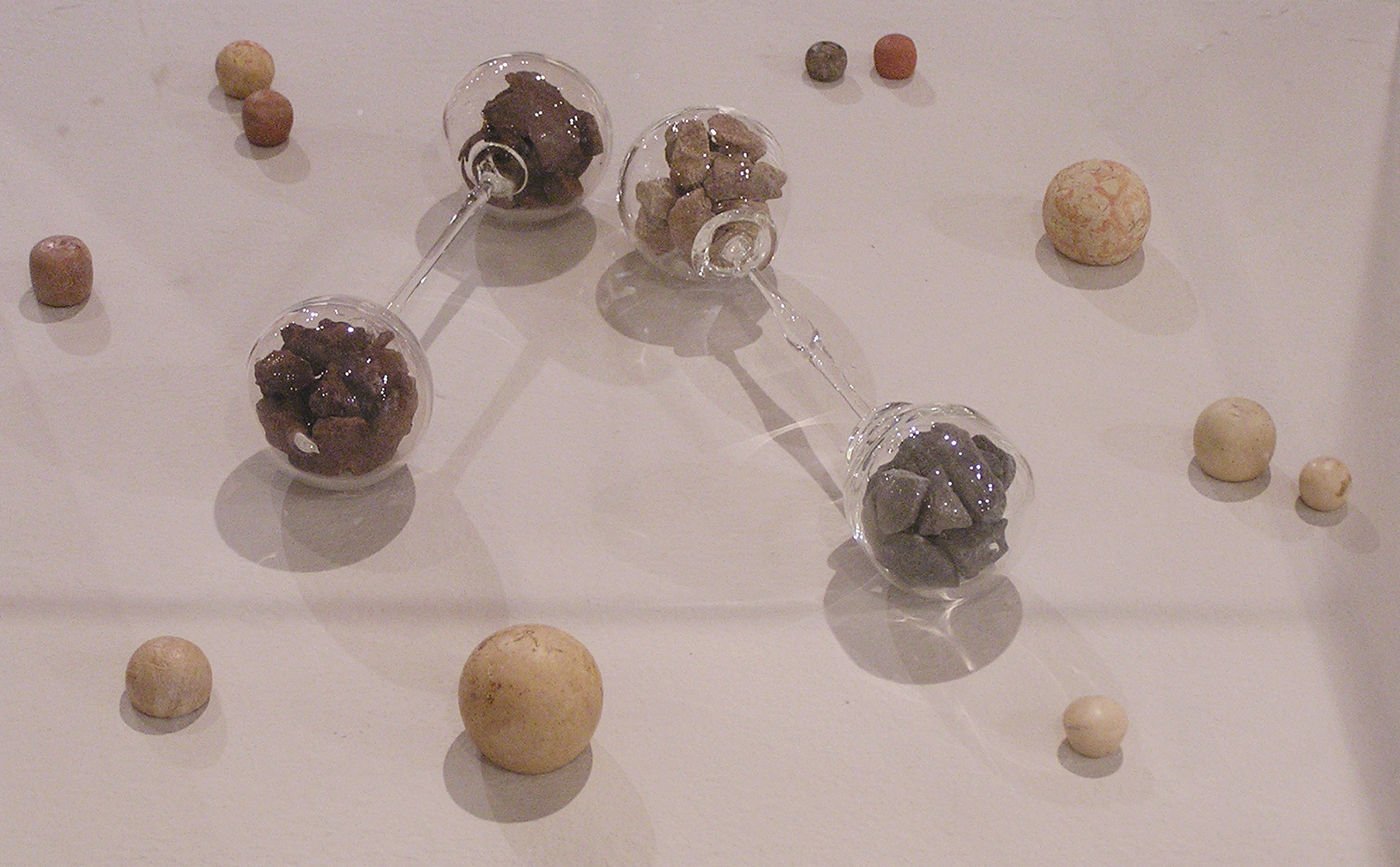 Inheritance , 2004, glass baby barbell rattles filled with stones surrounded by a group of twelve BCE stone shekel weights