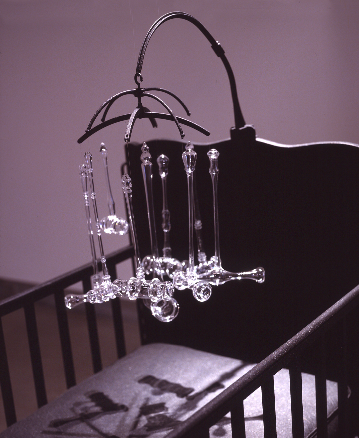 Detail of INFANT JUSTICE, 2002 crib with mobile consisting of nine glass gavels