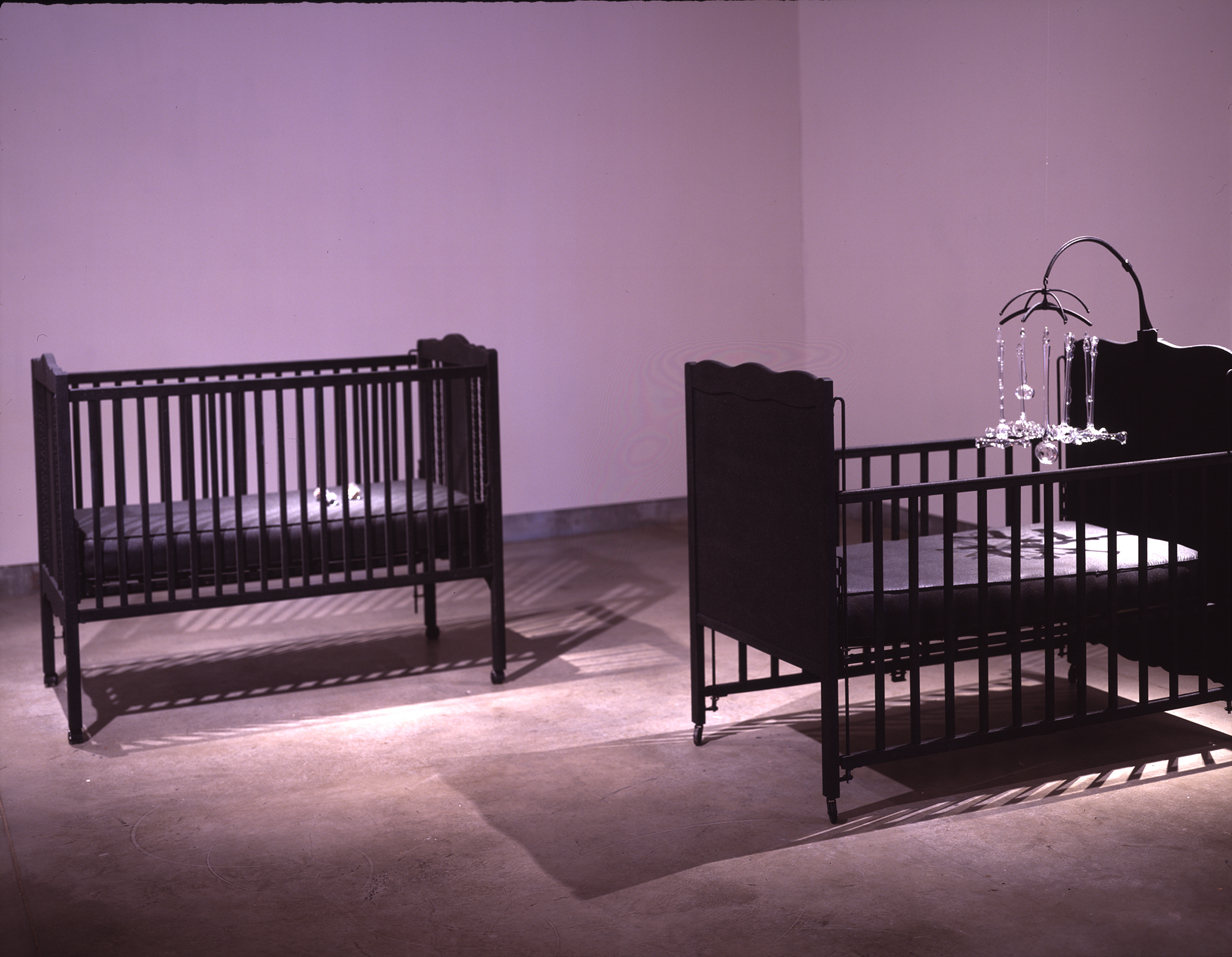 INFANT JUSTICE, 2002 two cribs with mobile consisting of nine glass gavels