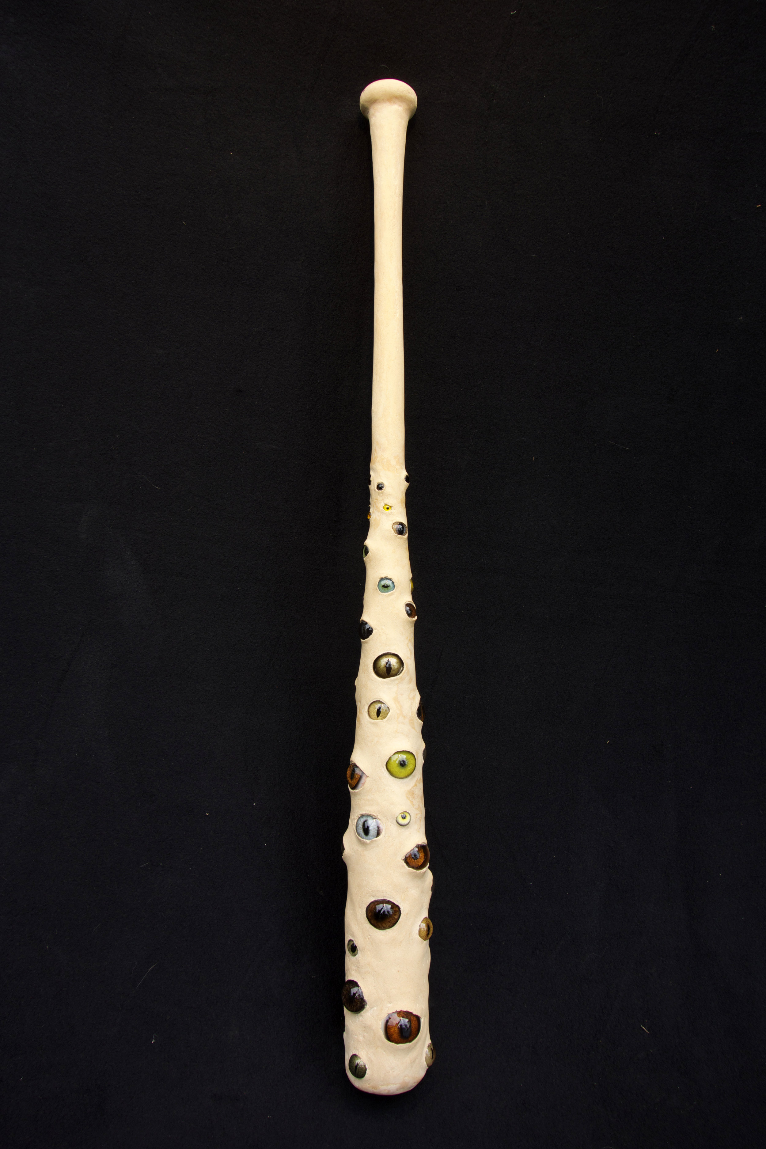CHOKE: WITNESS FOR PEACE 2017 Wooden baseball bat, epoxy filler, glass eyes, 33 x 3.5 x 3.5 inches The original version was made in 1998 but is now lost. Reconstructed in 2017. Glass eyes courtesy of Tohickon Glass Eyes with special thanks to Antonio Alfaro. On June 17, 1999, National Public Radio reported on British paratroopers who had found a baseball bat in a torture chamber in Pristina, Kosovo. The bat was inscribed with the label "mouth-shutter.” The existence of torture and its tools persists, despite so many eyewitness accounts and exposes. It is practiced before, during and after wars, overtly and covertly. Those it would harm flee if they can, joining refugees who seek a fundamental safety that home and state no longer provide. Borders define who lives and dies as we watch, eyes wide open. Witnessing without action is the choke—vision squandered and humanity abandoned amongst the rhetorical handwringing. “But witnesses incur responsibilities, as anyone who has ever seen a traffic accident and had to go to court to testify, knows. In the new world of globally televised war crimes, the defence of 'not knowing,' or neutrality, will dissolve for everyone. To be a witness or bystander is not a value-free choice but, inadvertently, a moral position; and in this sense the 'guilt' of people who live with the memory of crimes committed by members of their families, or communities, has been unwittingly extended to everyone who watches appalling pictures on the news.” ― Erna Paris , Long Shadows: Truth, Lies and History