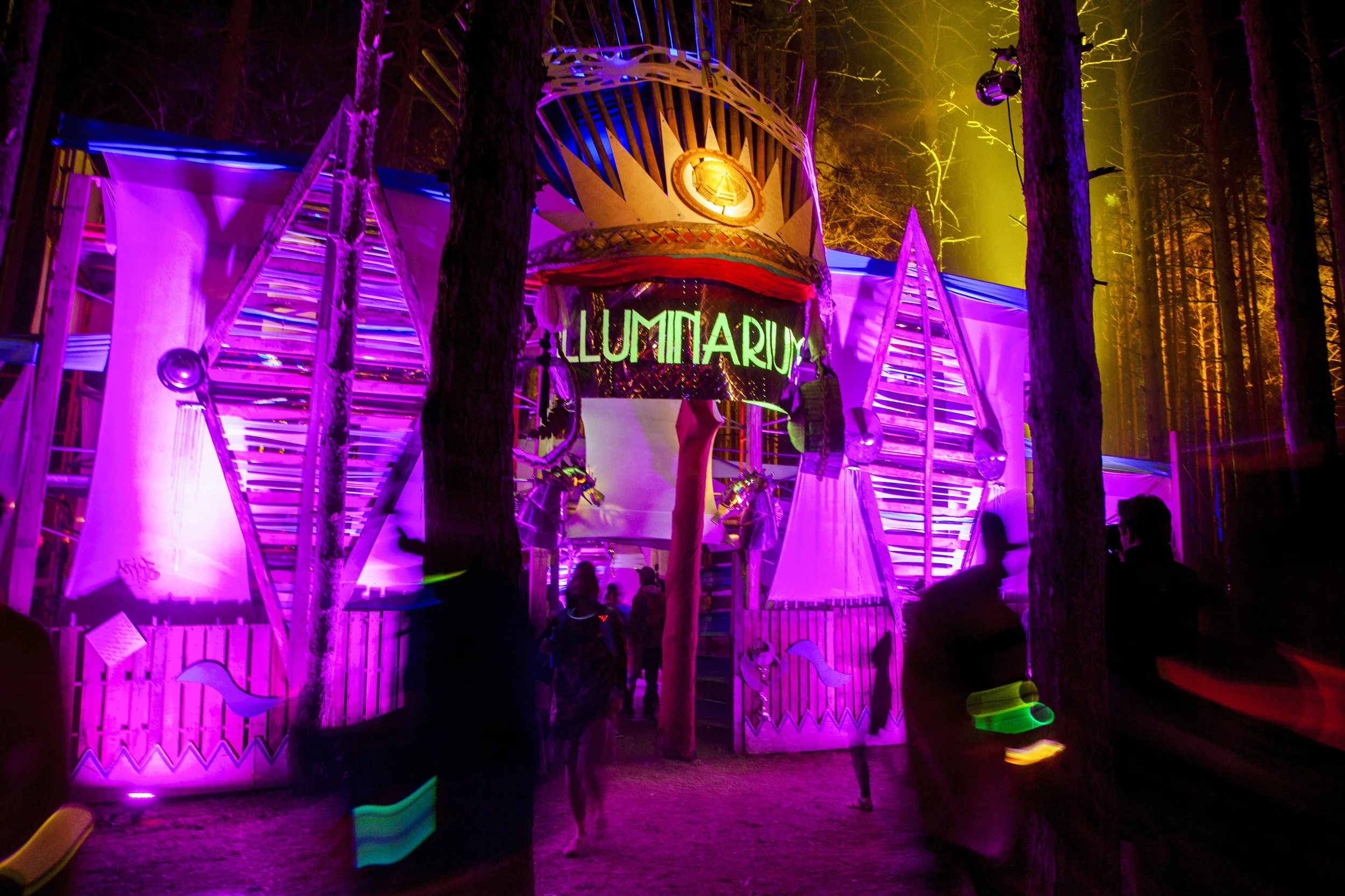 Festival goers explore the Lluminarium at night to experience the wonder of light and color in the Sherwood Forest.