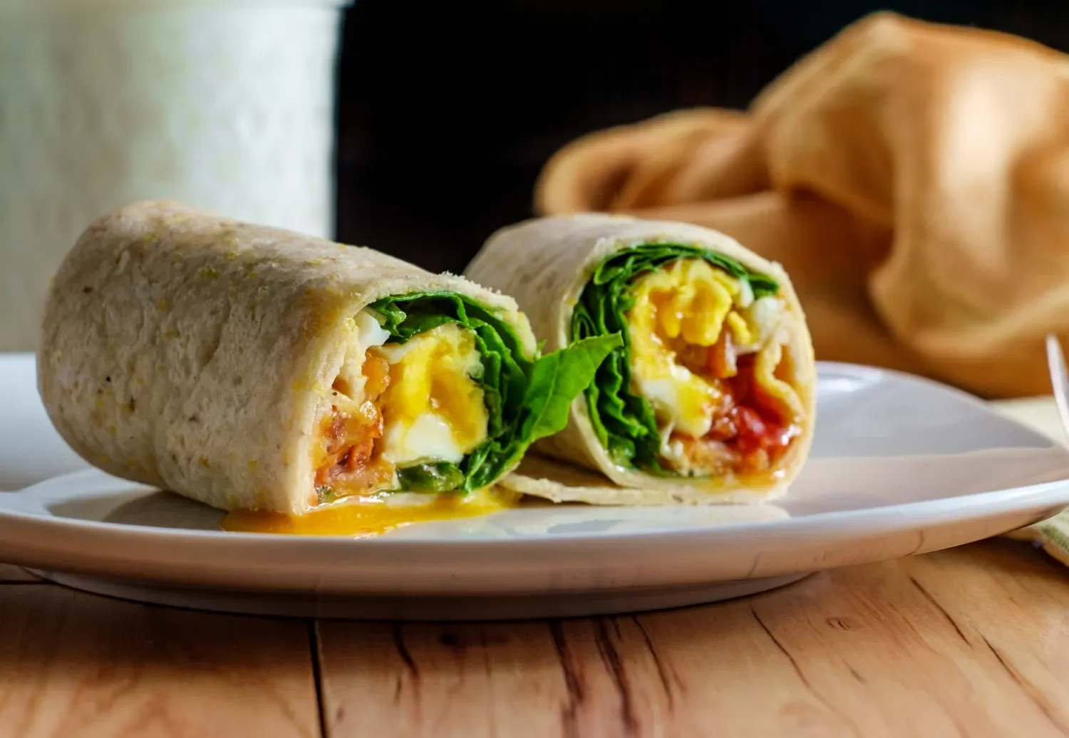 egg breakfast wrap cut in half view.  Eggs tomatoes spinach.