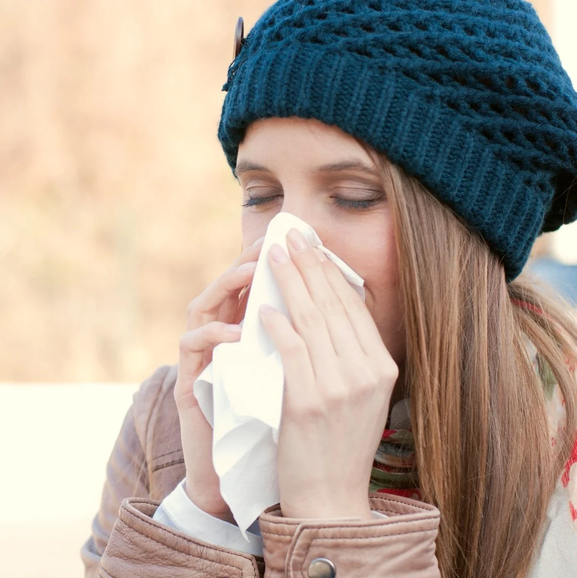 woman in a hat blowing her nose