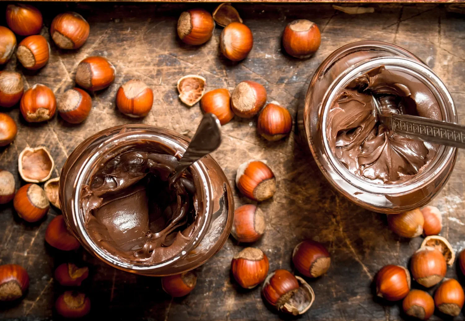 jars of hazelnut spread surrounded by hazelnuts
