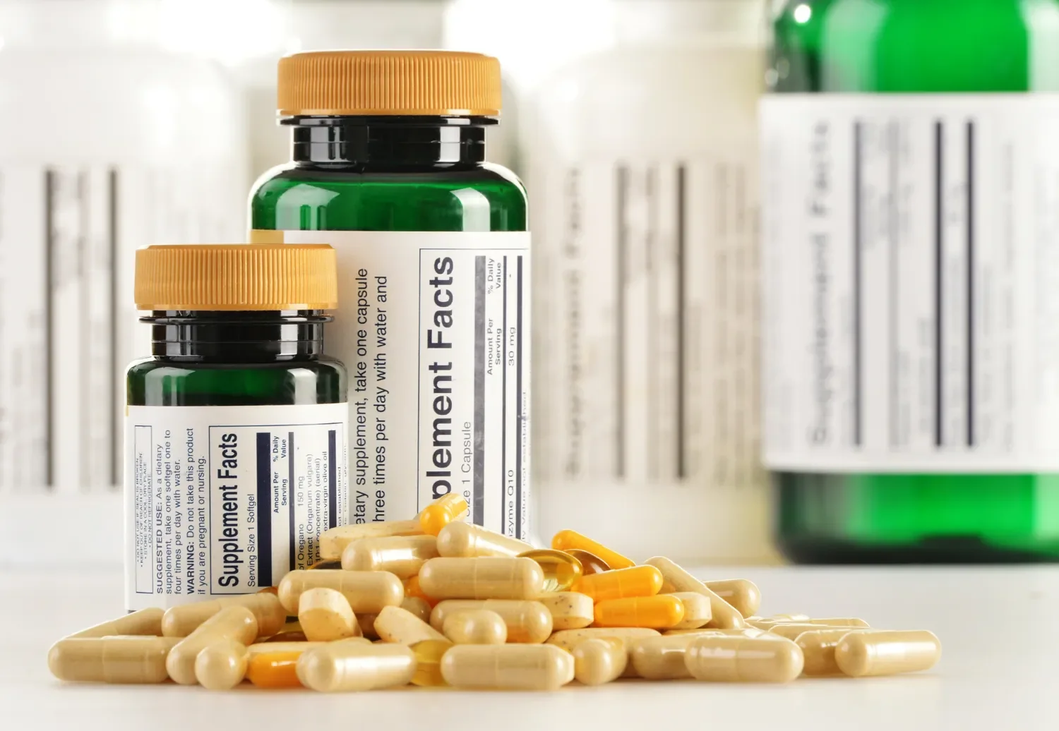 image of supplement bottles showing the supplement facts in the background with a pile of capsules and tablets in the foreground