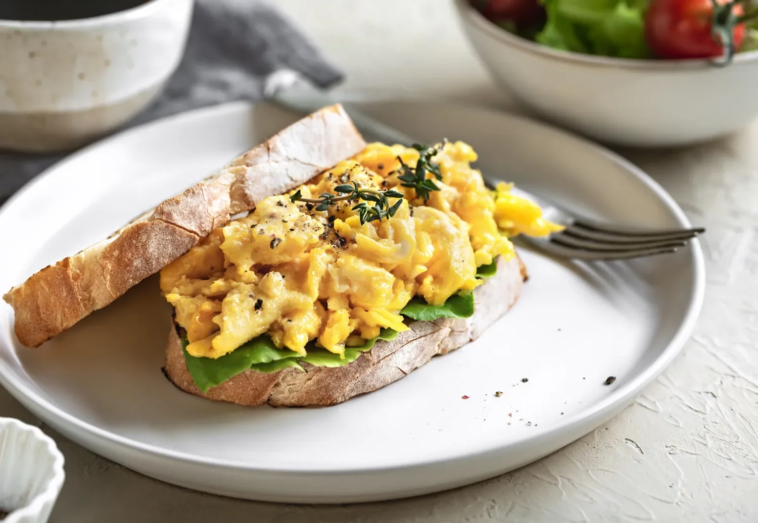 egg sandwich on rye bread on a plate with a salad