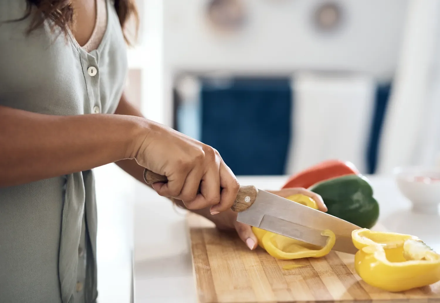 woman slicing peppers on a cutting board in a kitchen