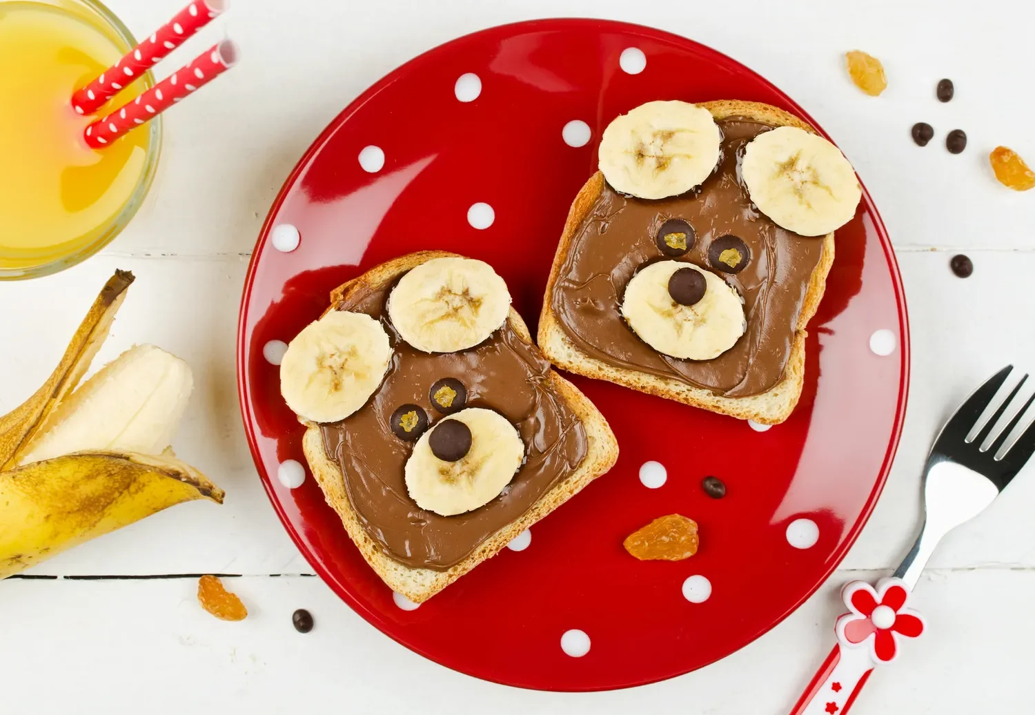kids breakfast toast on a plate with a bear face made of bananas and chocolate with a glass of orange juice