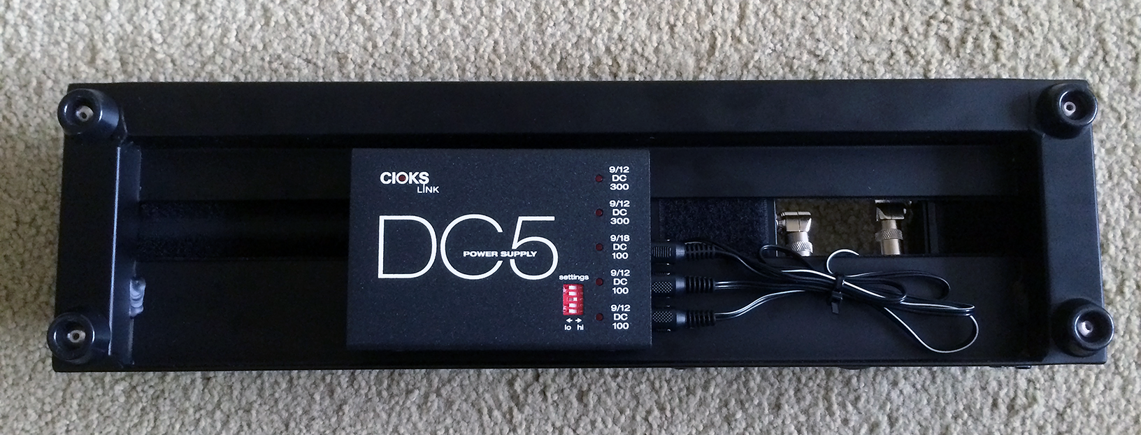 The Cioks DC5 power supply mounted under a Pedaltrain Nano+ pedalboard.