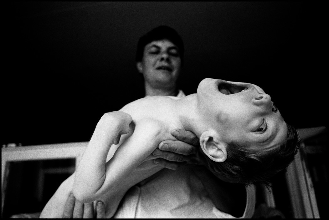  BELARUS. 1997. Children's Home #1, Minsk. An attendent bathes a helpless four-year-old child with multiple sclerosis. 