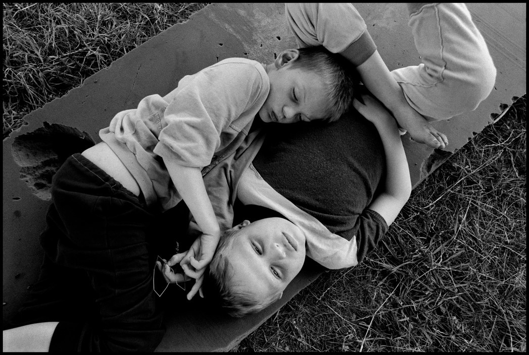 Two young boys find comfort in lying together in the summer sun. Novinki Asylum., Minsk, Belarus, 2000 .jpg