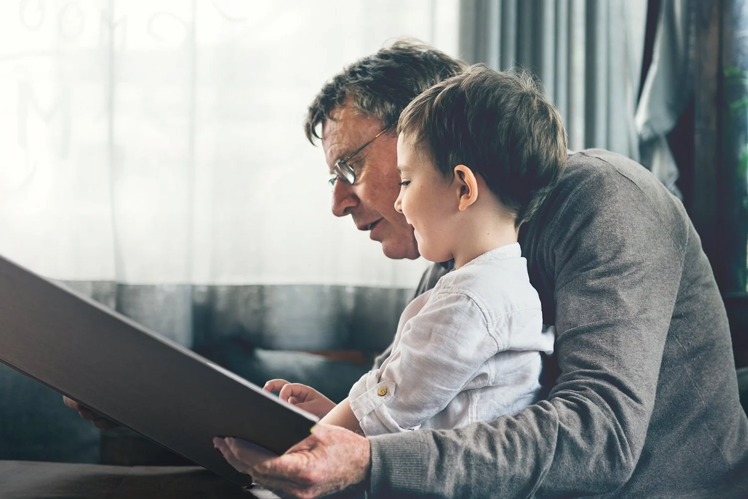 Grandfather and young child sharing a moment while reading together