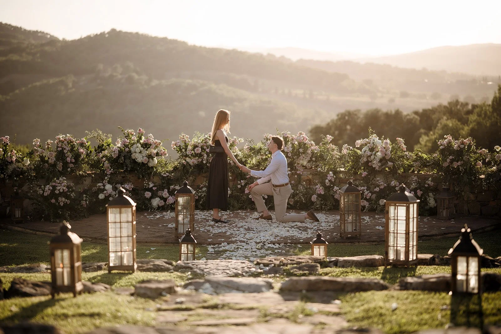 A romantic sunset marriage proposal on a Tuscan hillside terrace adorned with lanterns, romantic flower boxes, and sweeping panoramic views.
