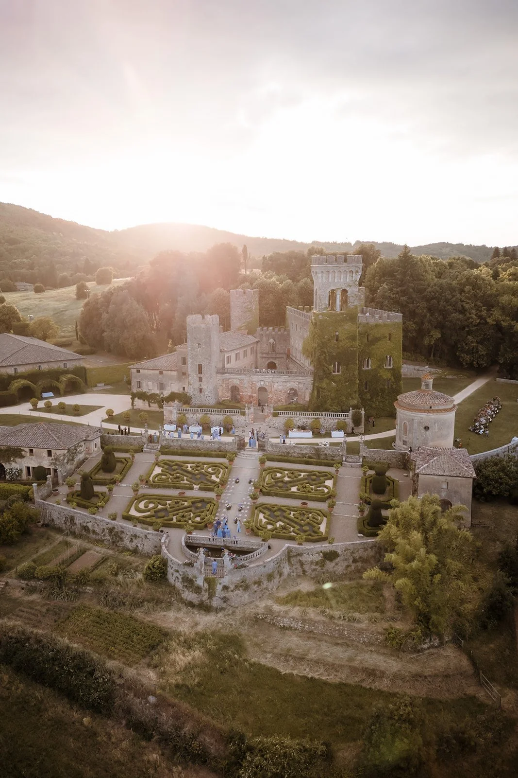 Aerial view of a historic luxury wedding castle and formal Italian garden in Tuscany set up for an exclusive destination wedding reception.