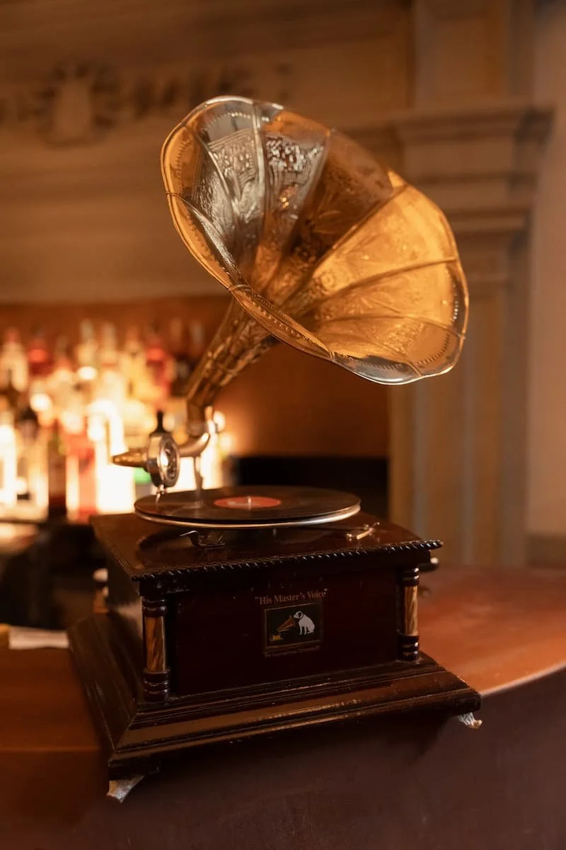 Vintage His Master's Voice brass horn gramophone displayed on a warm wooden bar counter at a wedding reception.