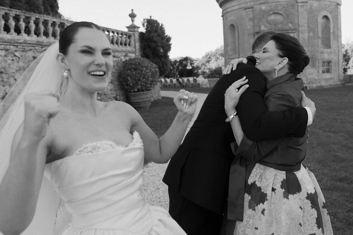 Joyful bride celebrating outdoors after wedding ceremony at a Tuscan villa with guests embracing.