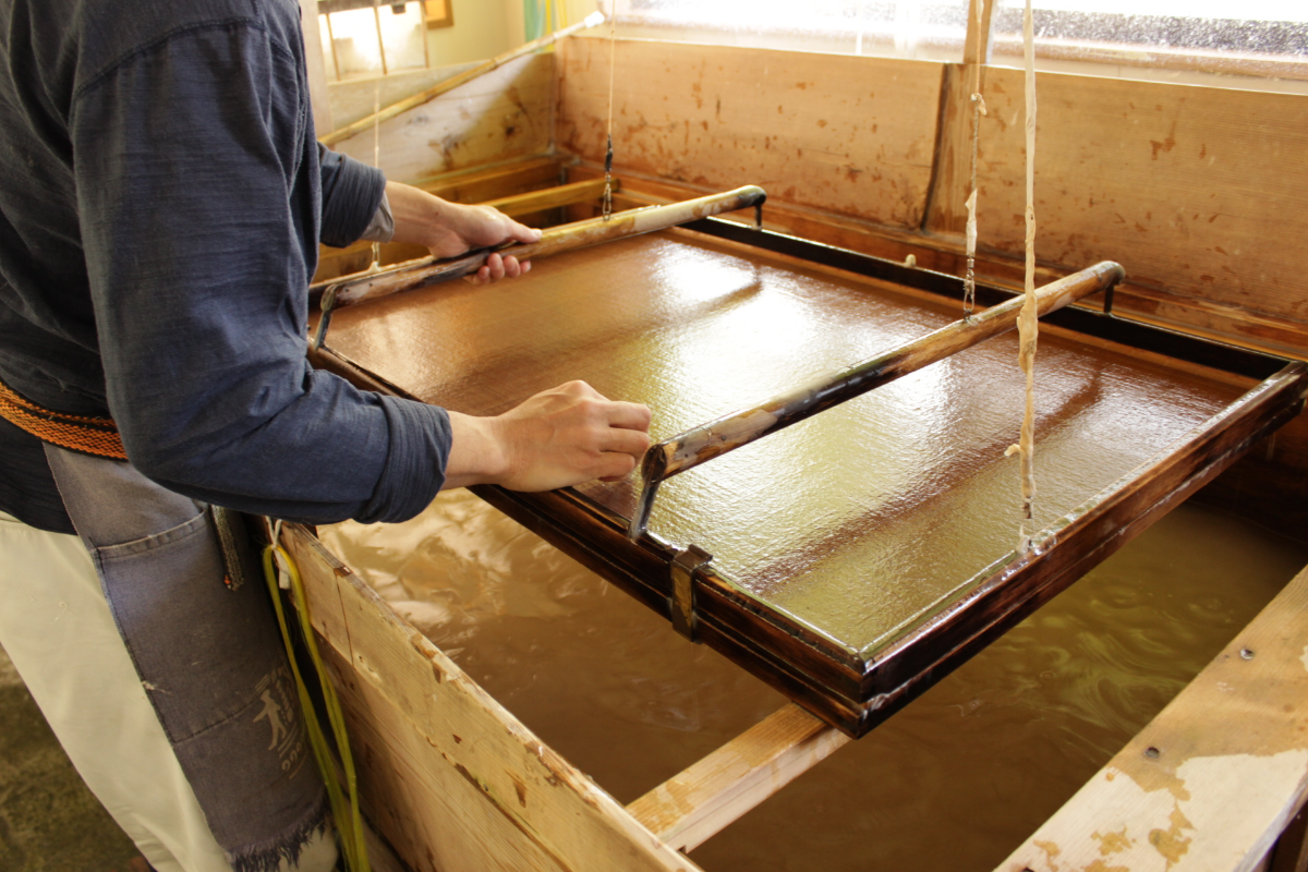 Artisan rocking the kozo fibers on a sogitsuke to form a sheet of paper. ©Japan Times