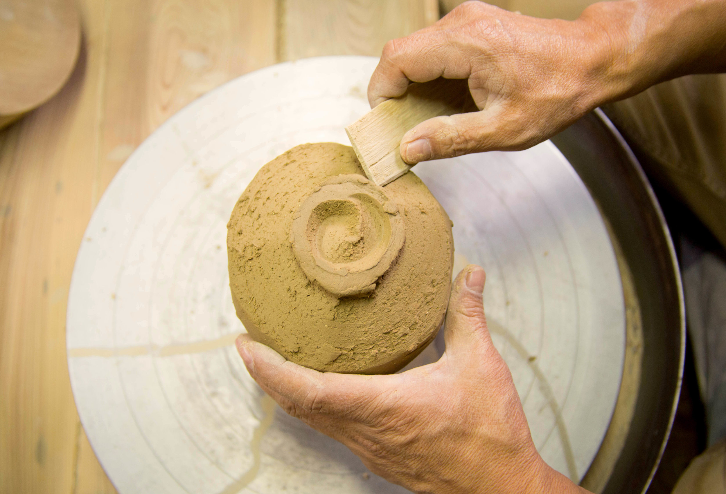 An artisan works on the base of a cup. ©TOKI