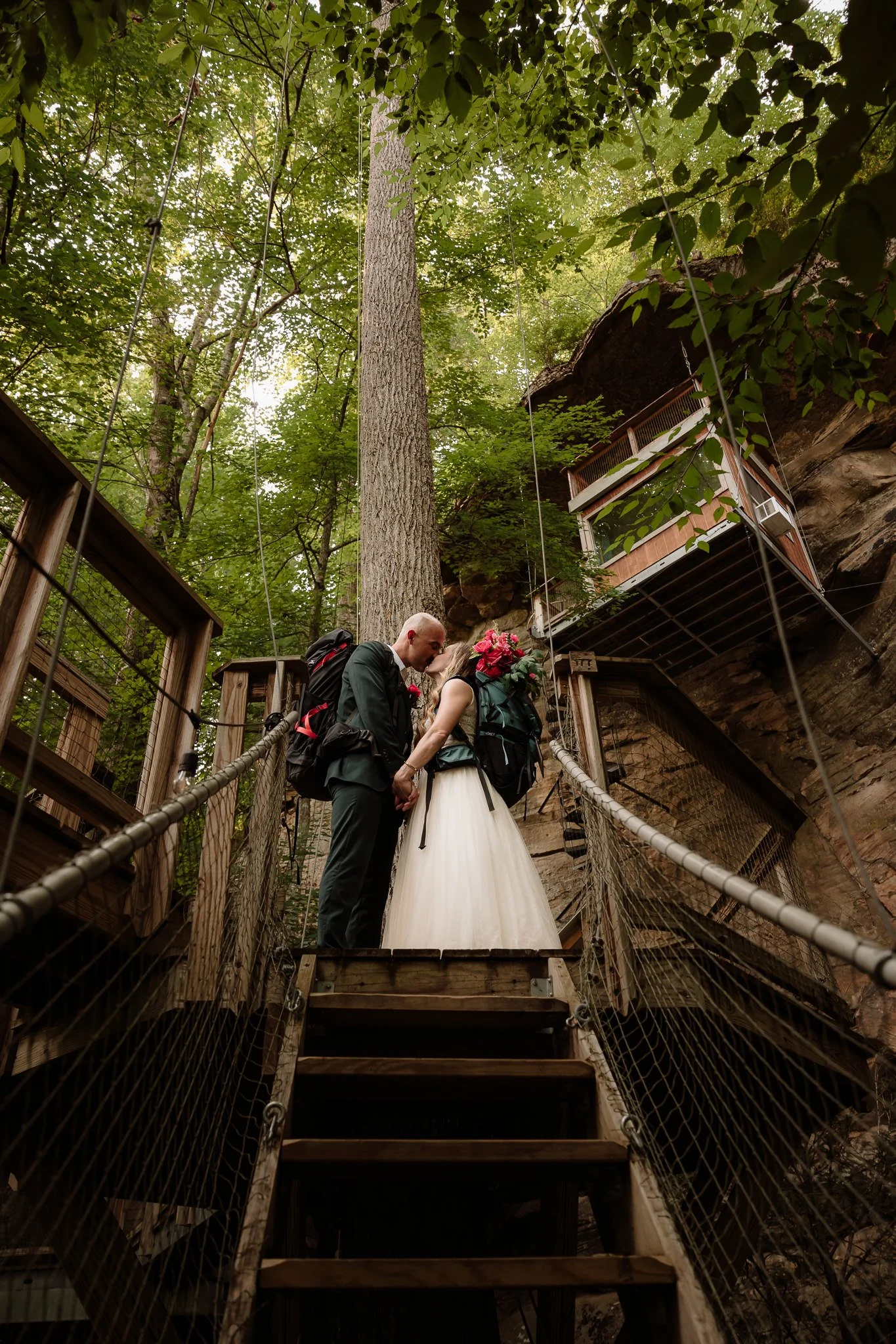 Elopement couple kissing while wearing hiking backpacks in Red River Gorge at a Canopy Crew treehouse