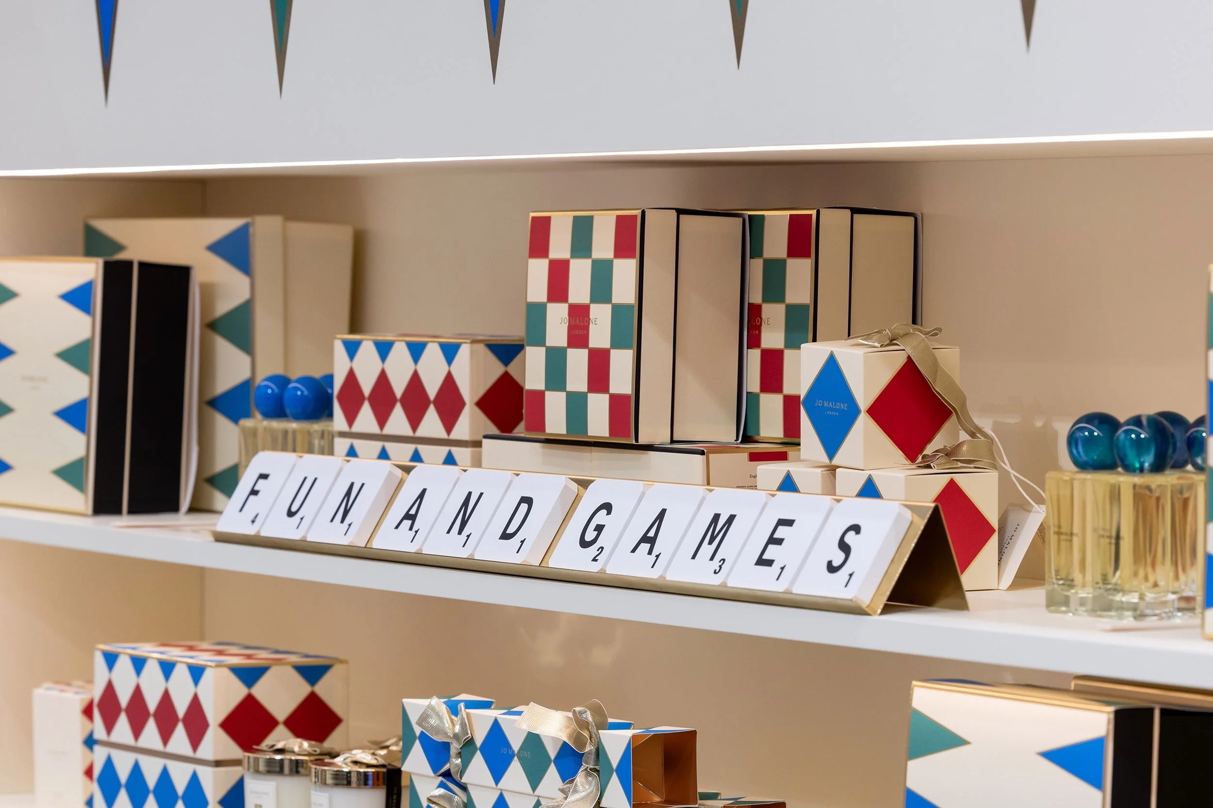 Close-up of custom solid bent brass Scrabble® tile holders with letter tiles fabricated by McWood for the Jo Malone London board game display at Holt Renfrew Centre in Toronto.