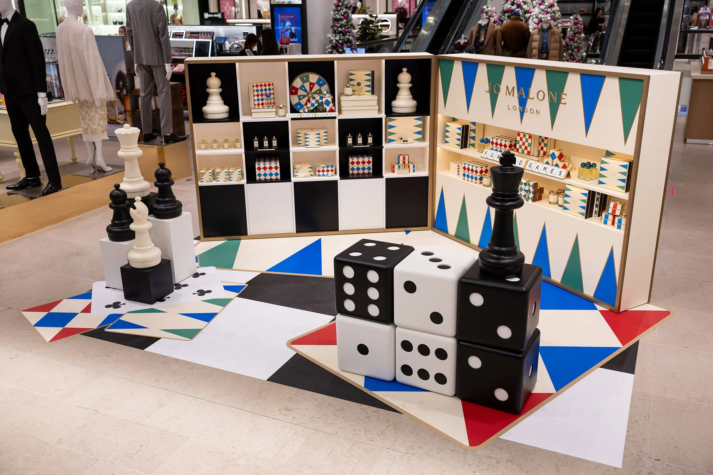 McWood's custom Jo Malone London board game display at Holt Renfrew Centre in Toronto featuring oversized wooden dice, illuminated game cabinets, brass Scrabble® tile holders, and custom acrylic lettering.