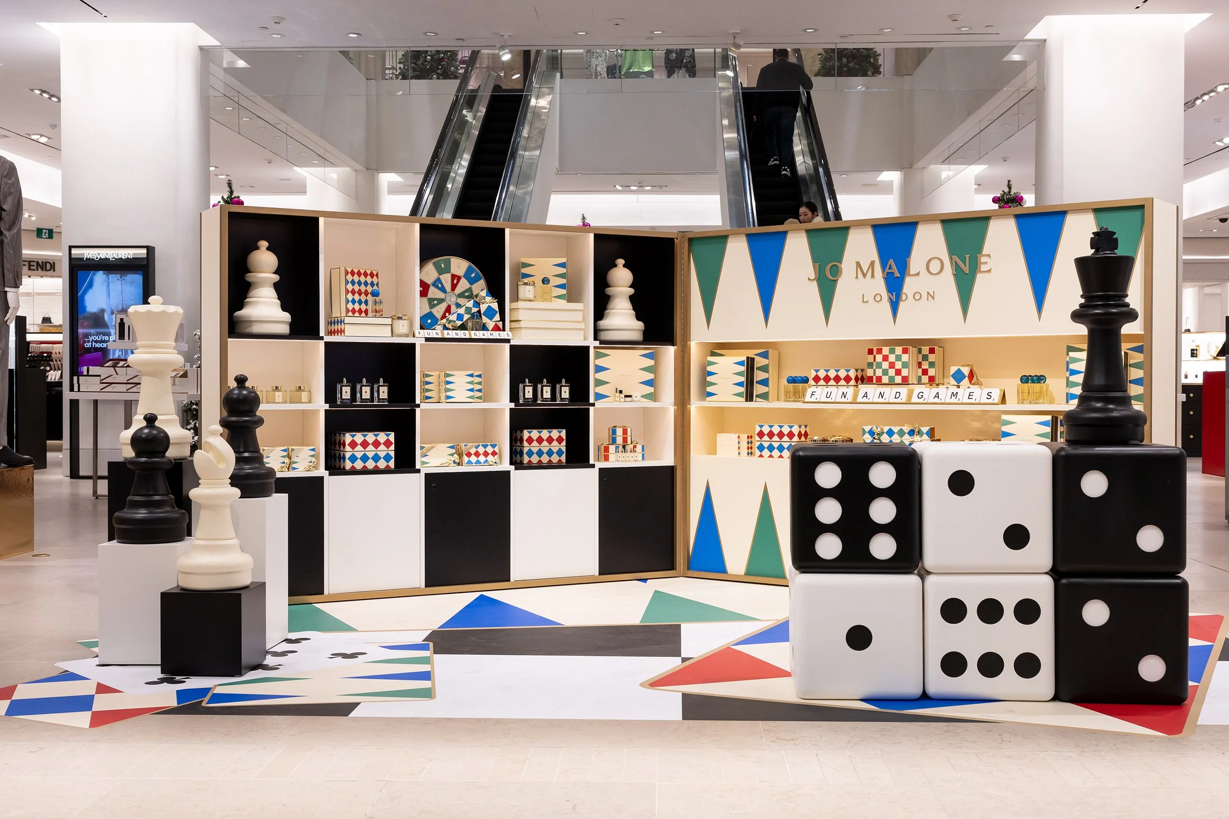McWood custom Jo Malone London board game display at Holt Renfrew Centre in Toronto featuring oversized wooden dice, brass Scrabble® tile holders, custom acrylic lettering, and illuminated game cabinets.