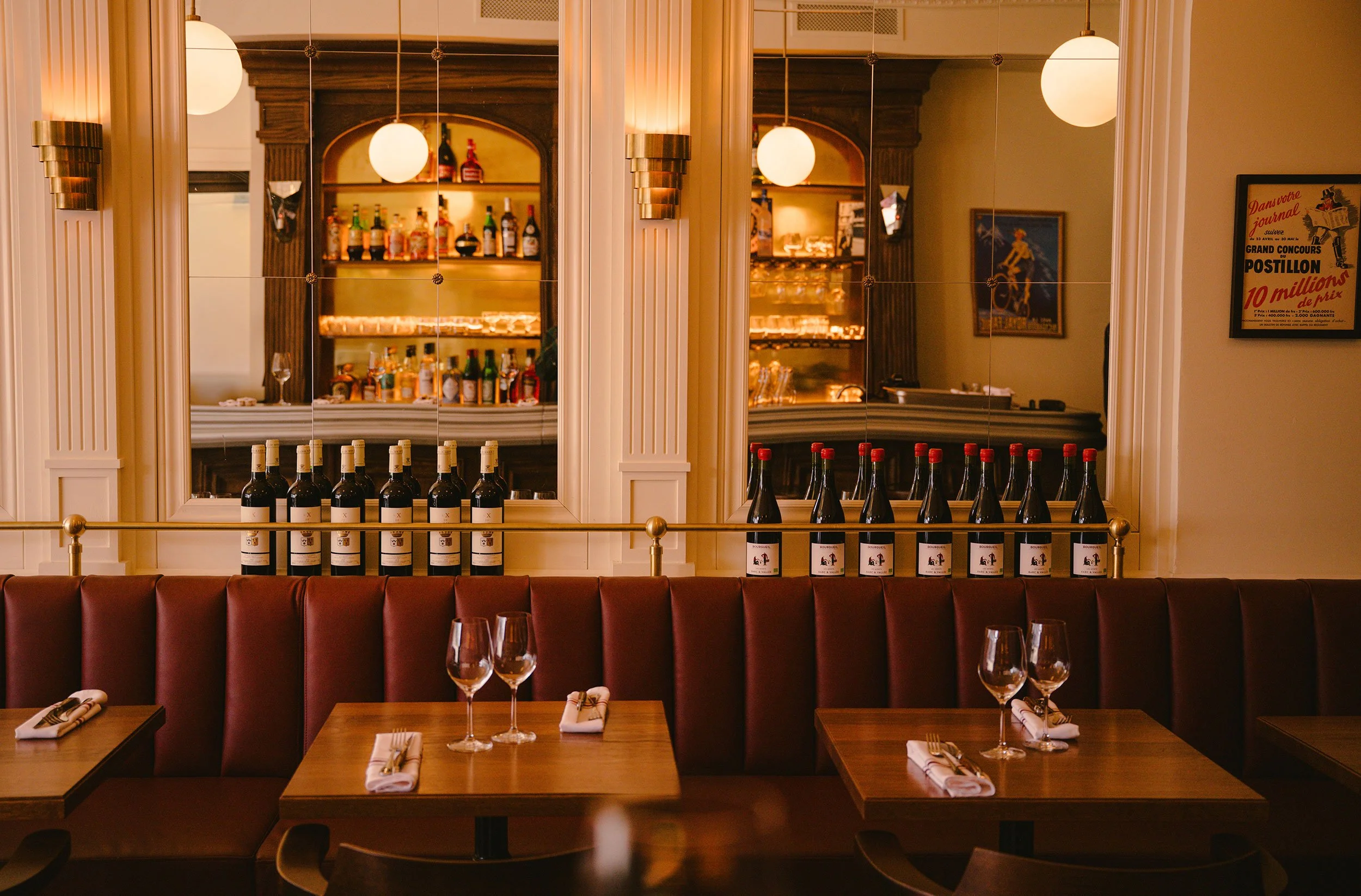 Custom feature mirror wall at Brasserie Côte, combining millwork and vintage globe lighting to enhance natural light and create depth.