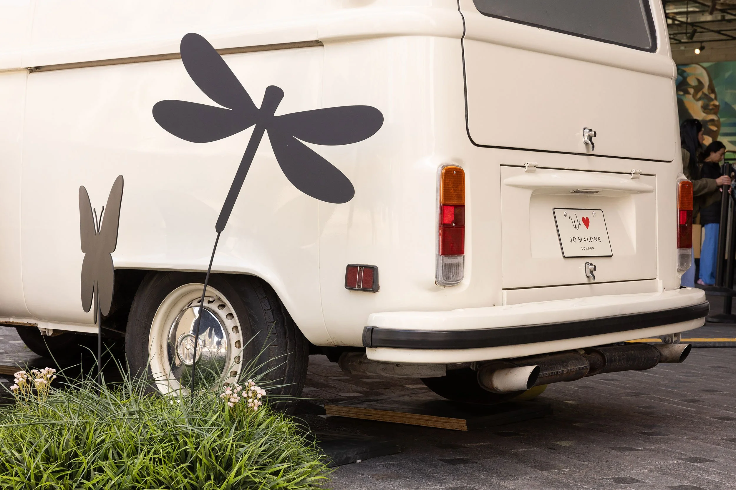 Close-up of the custom Jo Malone London vintage VW van by McWood featuring handcrafted oversized insects, flowers, and grassy details at The Well in Toronto