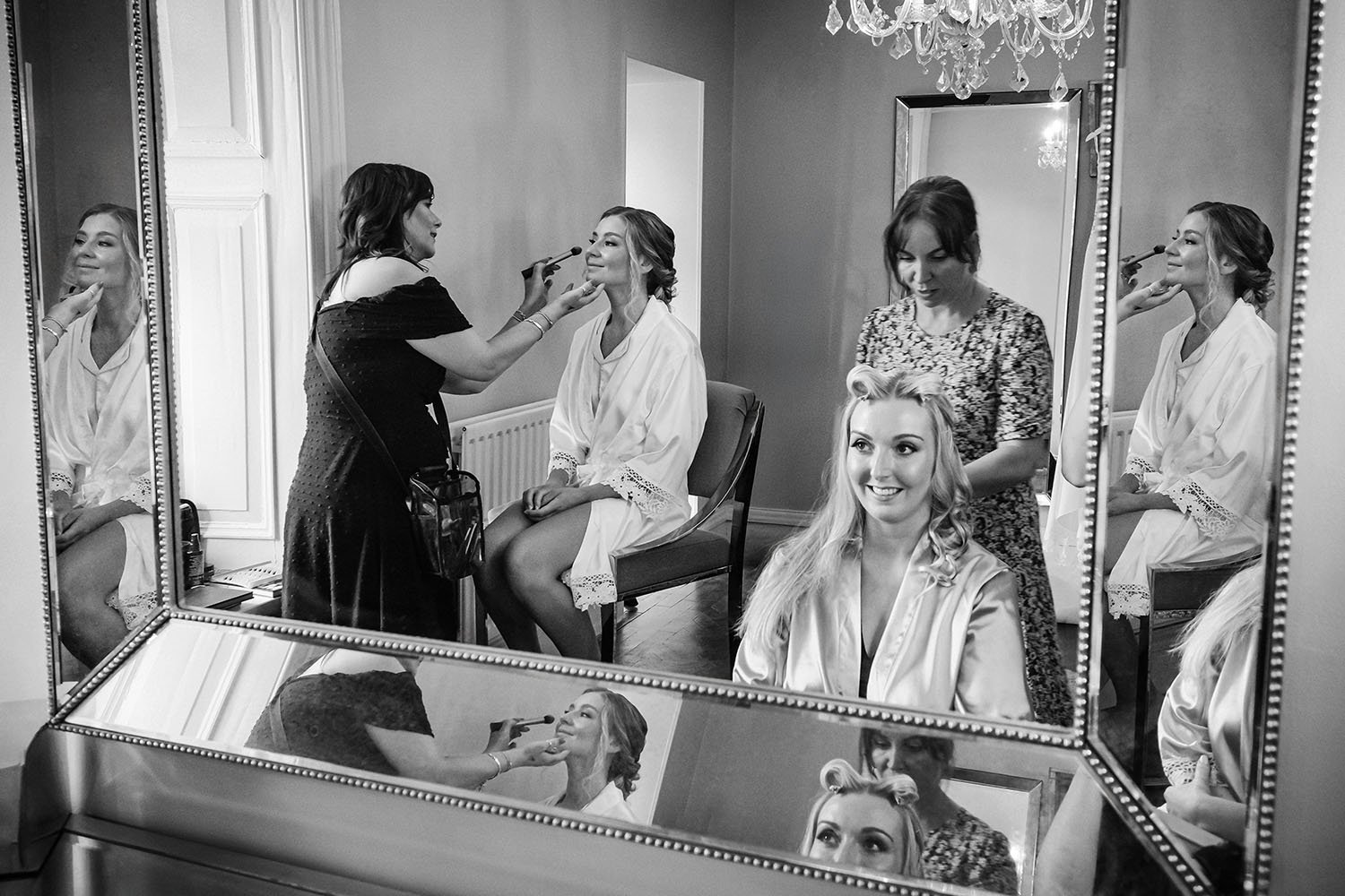 Ellingham Hall wedding: bride and bridesmaids in white robes having their makeup done