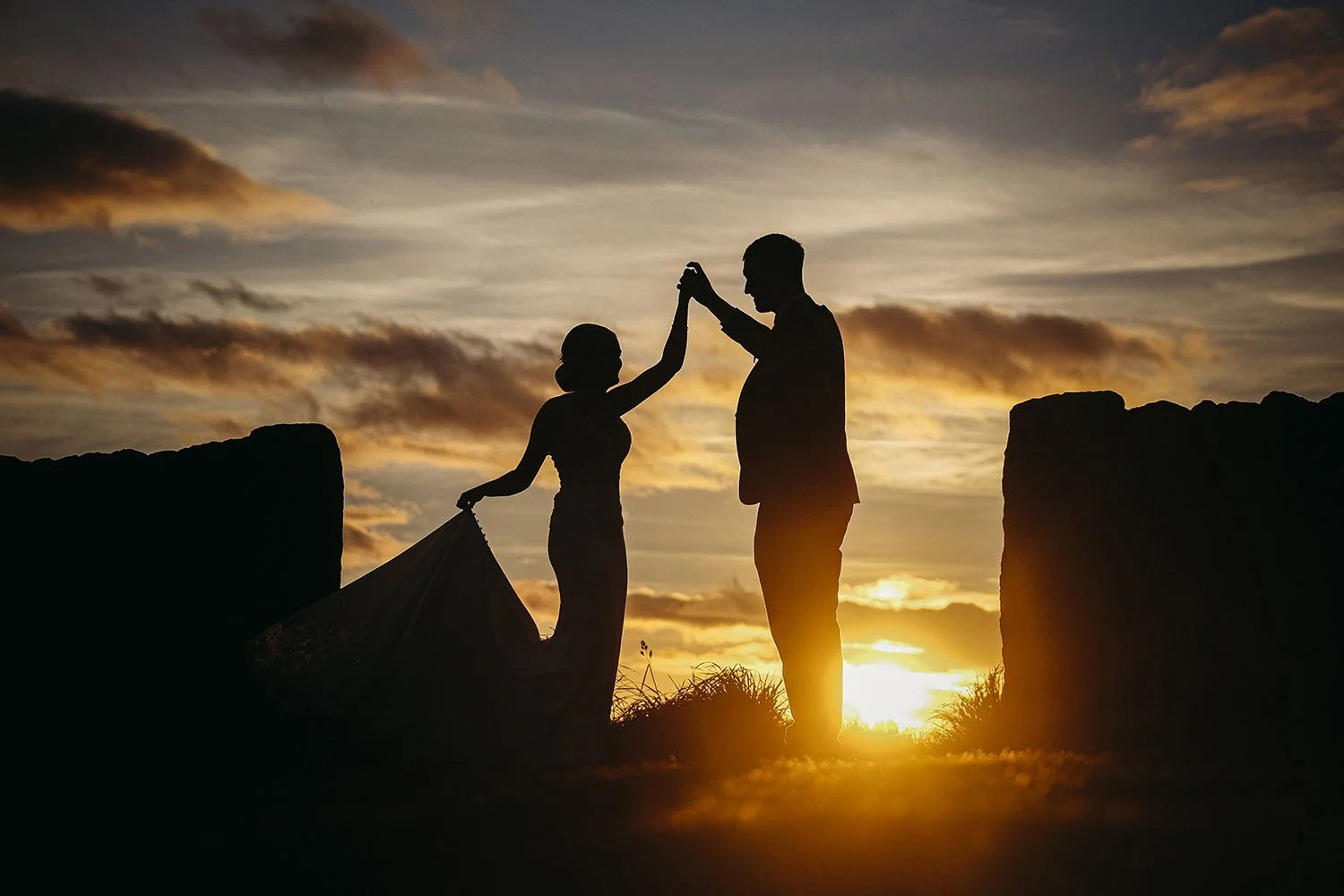 Silhouetted couple dancing at sunset between rocky cliffs