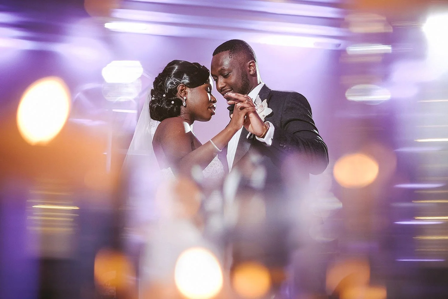 Beamish Hall wedding: bride and groom smiling during their first dance, surrounded by streaks of purple light.